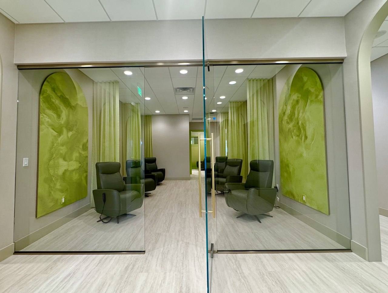 A glass-walled recovery suite with reclining therapy chairs.