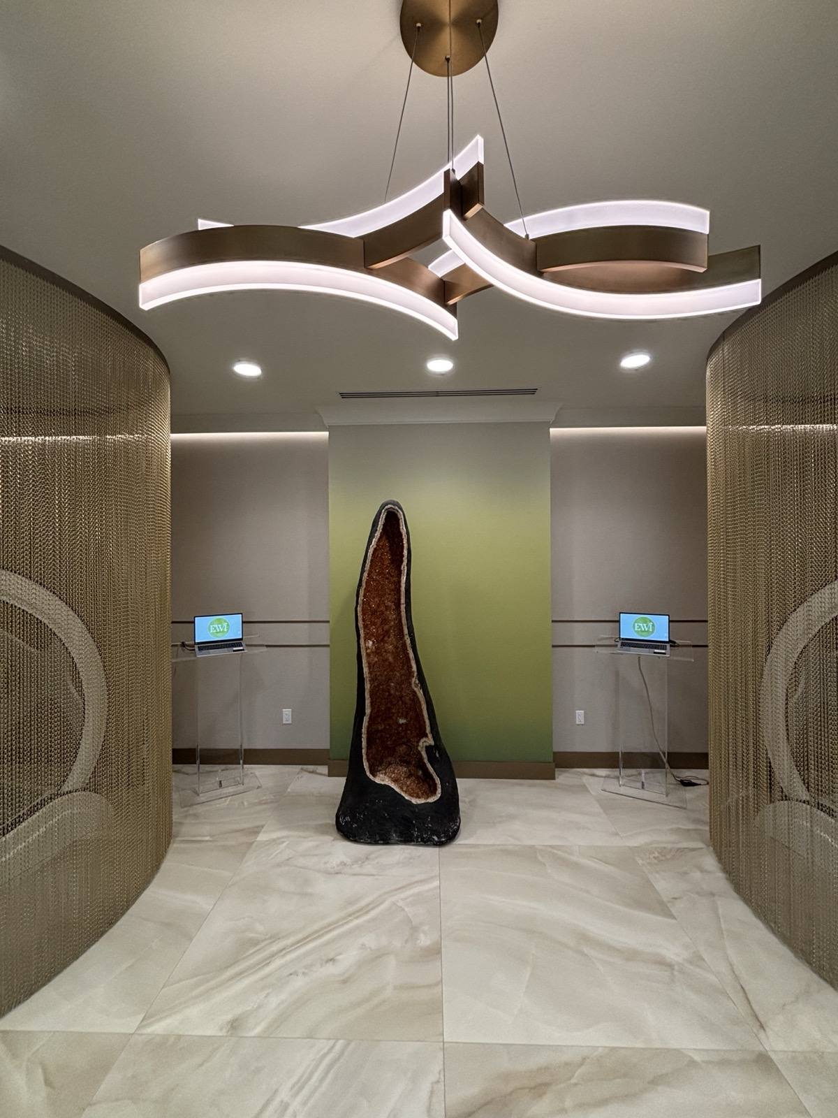 The amethyst geode at the heart of the lobby, framed by the gold-mesh pods.
