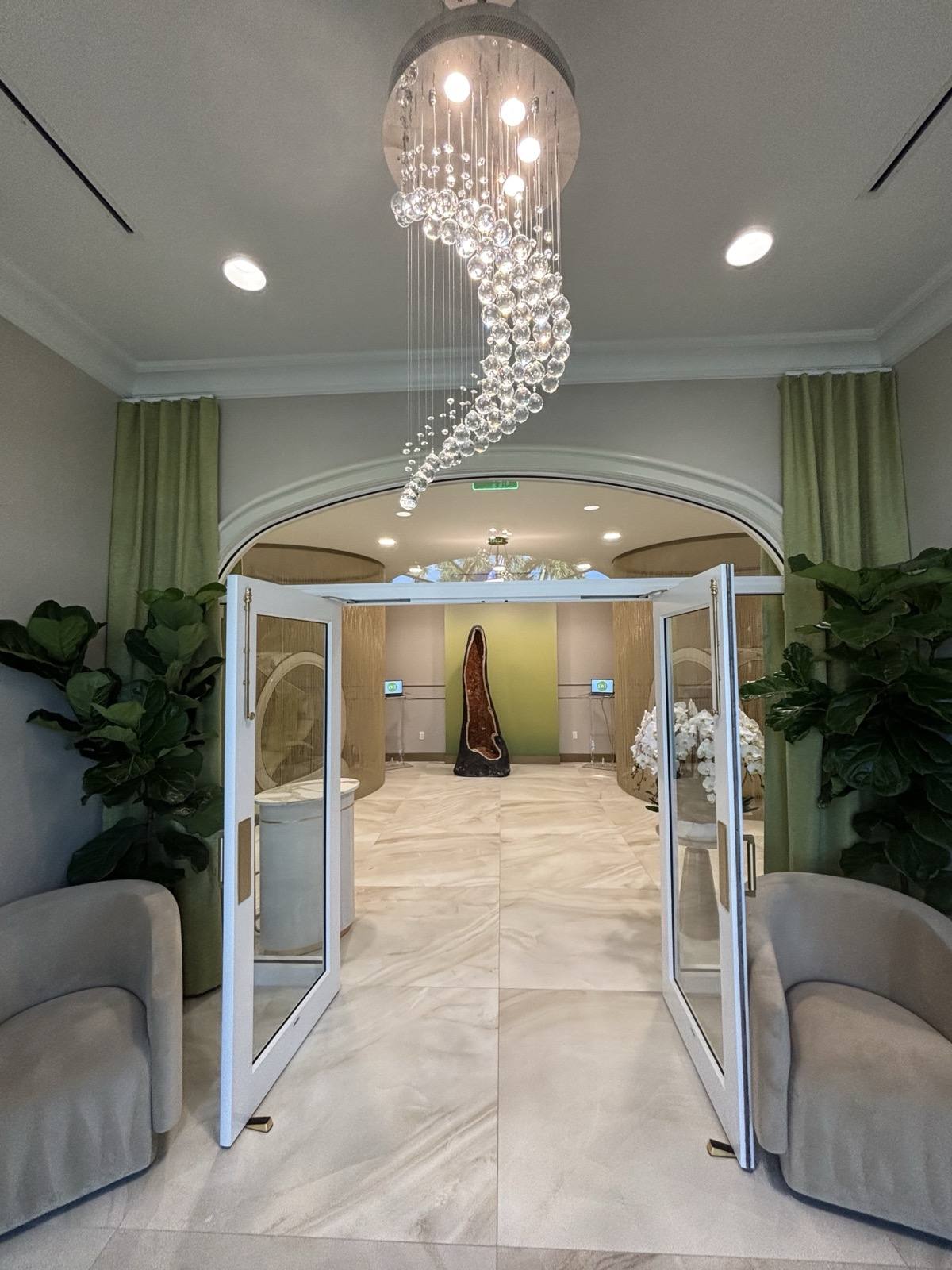 The entrance — a spiral crystal chandelier above the arched doors, the amethyst geode beyond.